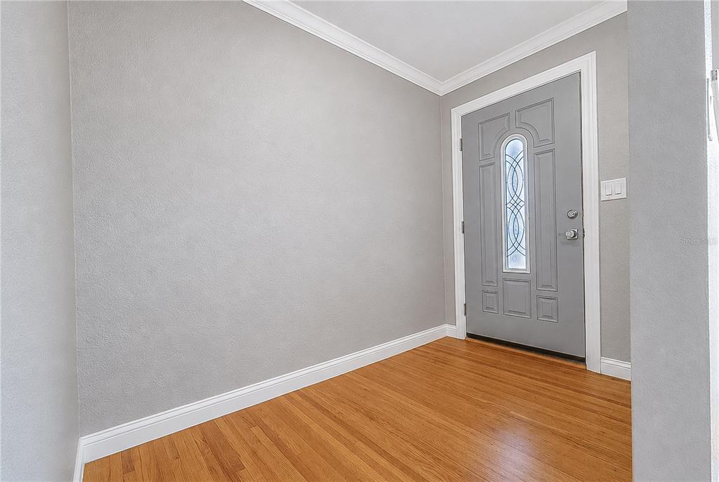 An entryway features light gray walls, white crown molding, and hardwood flooring — 1032 BEL AIRE DRIVE, DAYTONA BEACH, FL