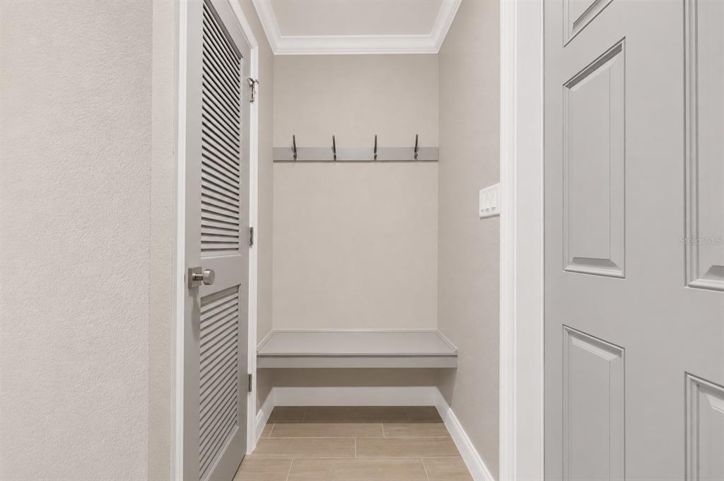 A small mudroom area features a built-in bench, wall hooks, and a louvered door — 1032 BEL AIRE DRIVE, DAYTONA BEACH, FL