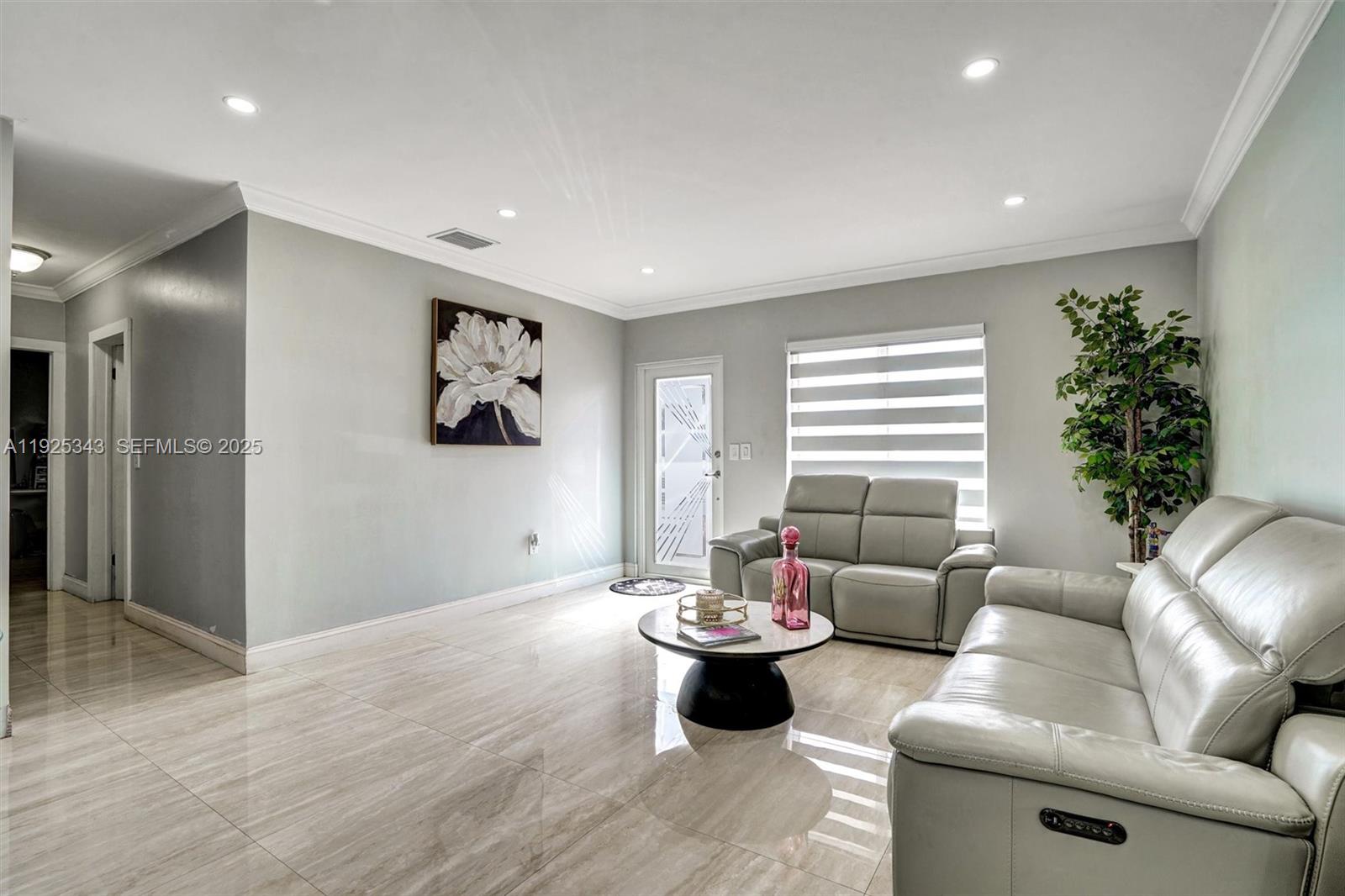 A modern kitchen features white upper cabinets, gray lower cabinets, a waterfall island, and stainless appliances — 631 E 53rd St, Hialeah FL 33013, HIALEAH, FL