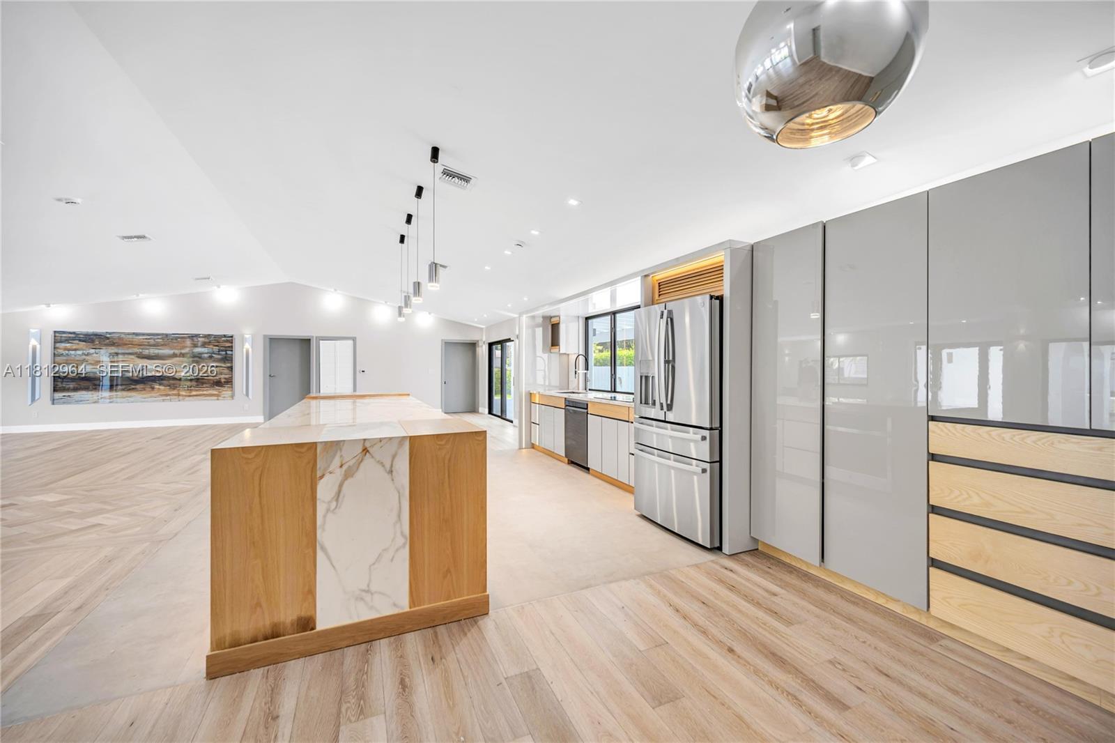 A modern kitchen features a marble-topped island, light wood cabinetry, and stainless steel appliances — 10600 SW 140th St, Miami FL 33176, MIAMI, FL