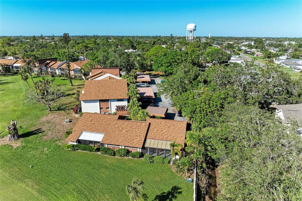 An aerial view shows a multi-unit residential building with brown roofs and surrounding green landscaping — 4644 RED MAPLE ROAD UNIT 1303, BRADENTON, FL