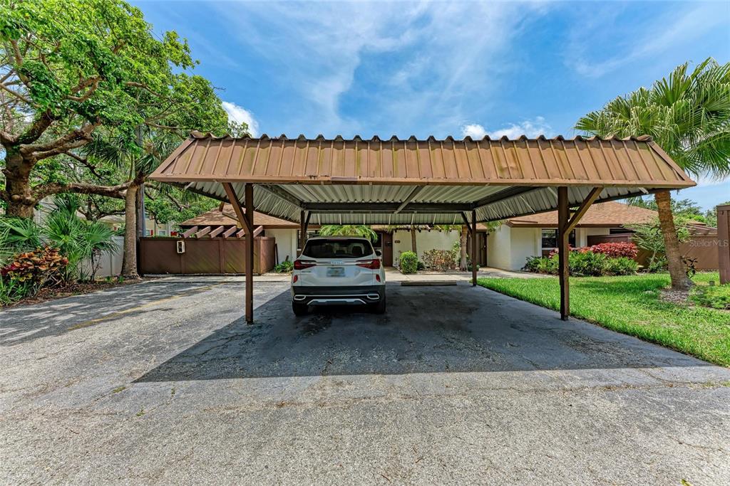 A white SUV is parked under a metal carport in front of a single-story house — 4644 RED MAPLE ROAD UNIT 1303, BRADENTON, FL
