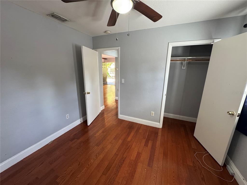 A bedroom with gray walls, hardwood floors, a ceiling fan, and an open closet — 2276 RAEFORD ROAD UNIT A4, ORLANDO, FL