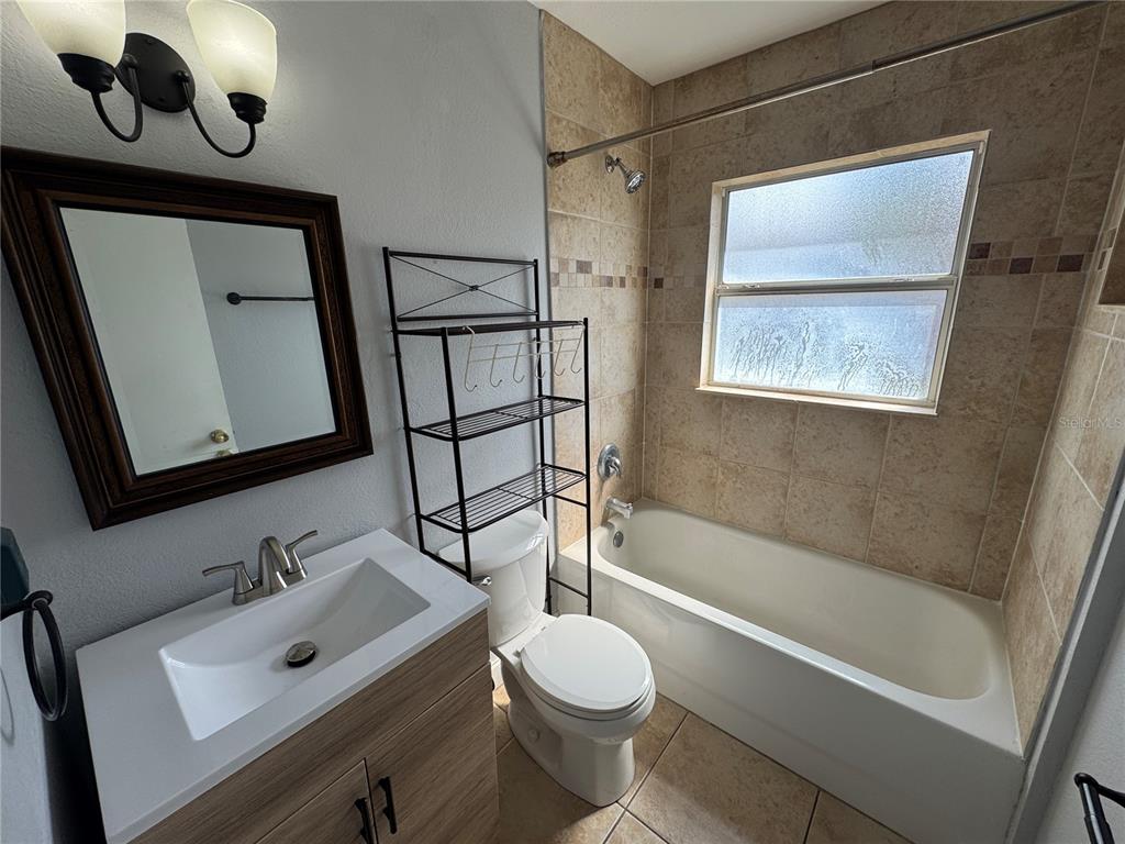 A bathroom features a vanity, a toilet with a shelving unit, and a tiled tub-shower — 2276 RAEFORD ROAD UNIT A4, ORLANDO, FL
