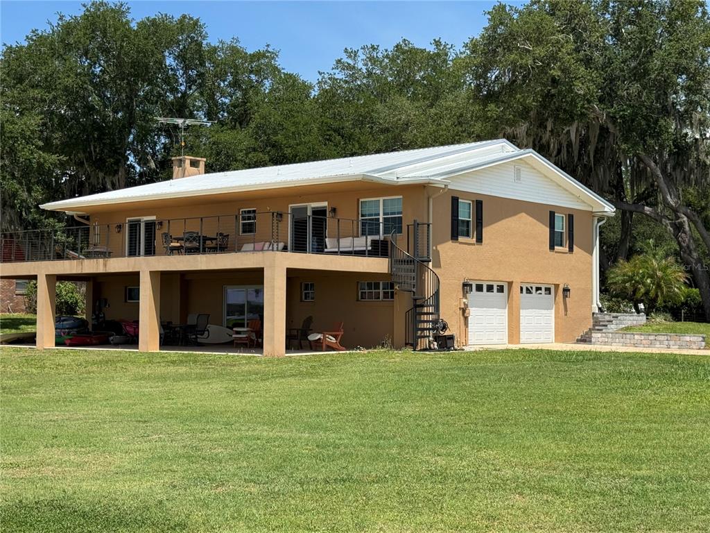 A two-story house with a large elevated deck, a spiral staircase, and a ground-level garage — 607 W STATE ROAD 630, FROSTPROOF, FL