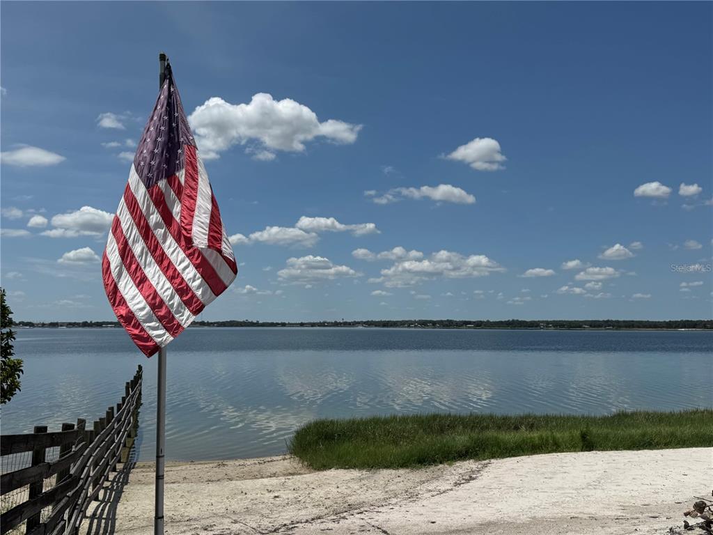 An American flag stands on a pole overlooking a lake with a sandy shore — 607 W STATE ROAD 630, FROSTPROOF, FL