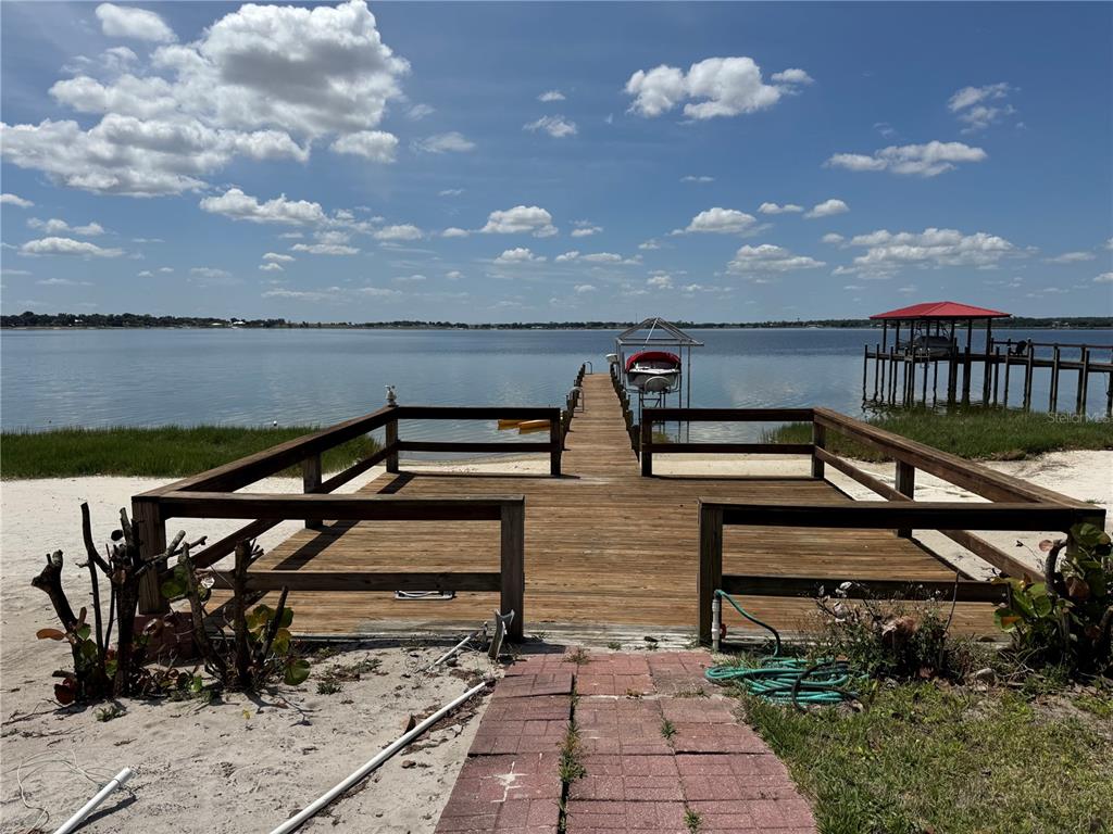 A wooden dock with railings extends into a lake under a blue sky — 607 W STATE ROAD 630, FROSTPROOF, FL