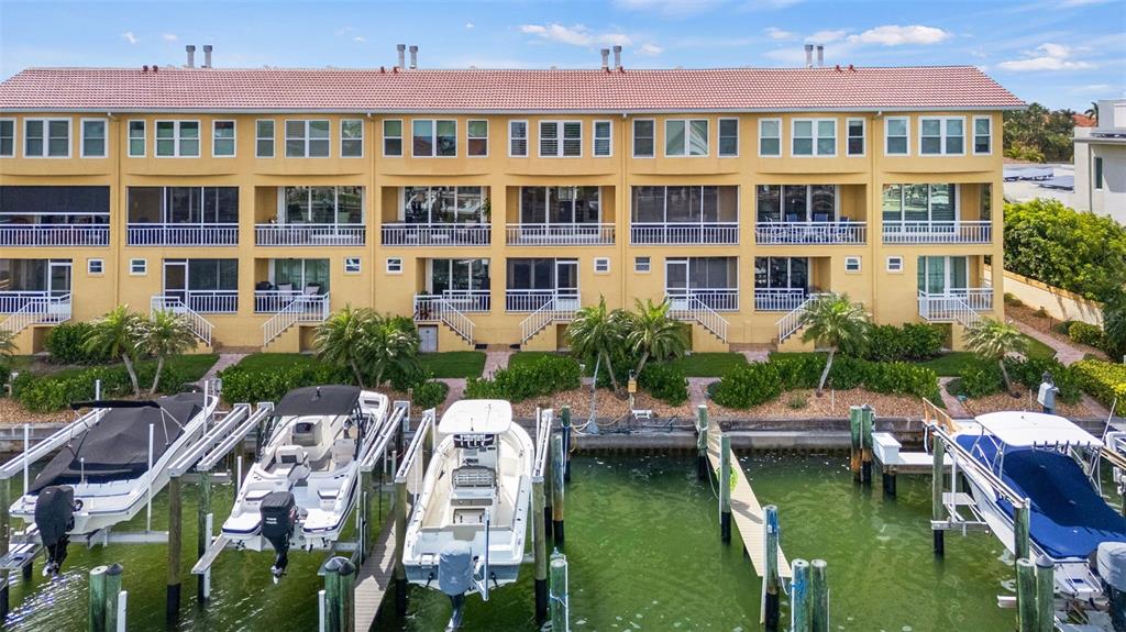 A multi-story yellow apartment building sits along a canal with several boats docked outside — 1071 PINELLAS BAYWAY S, ST PETERSBURG, FL