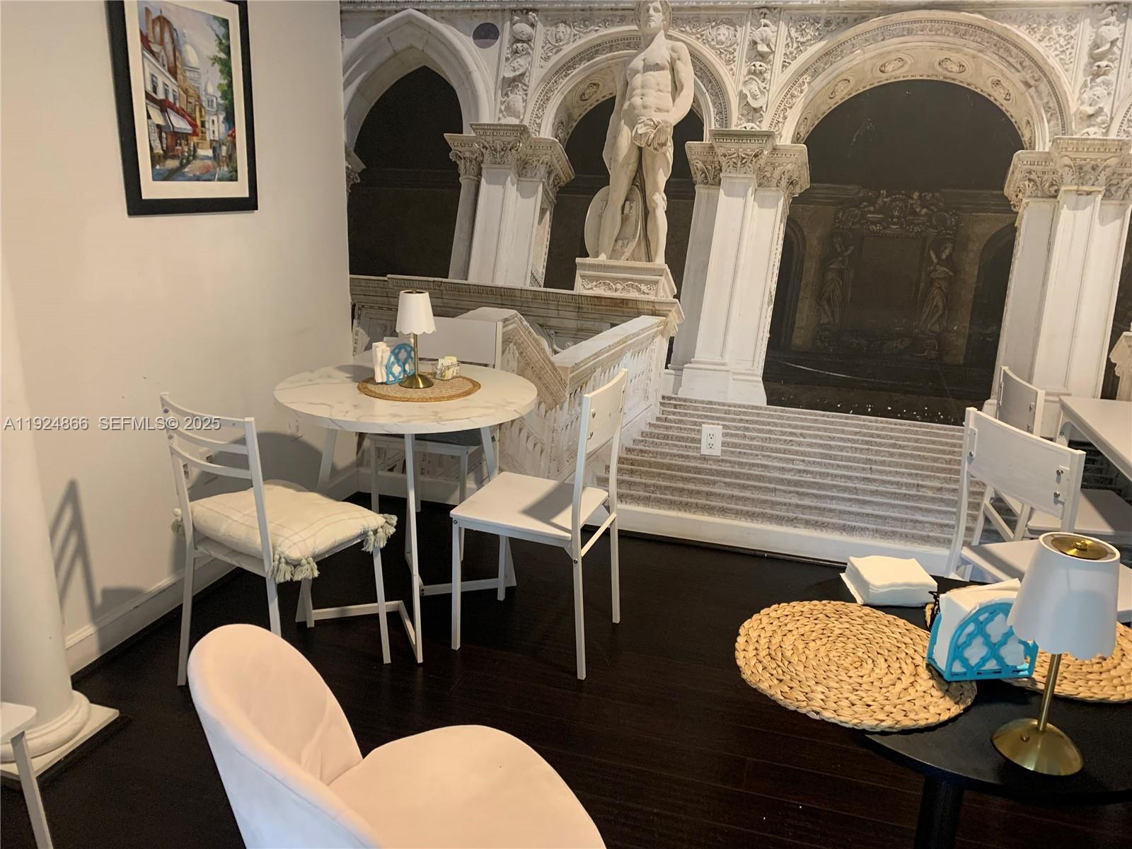 A dining area features a round table, white chairs, and a mural of a classical statue — 1239 Alton Rd, Miami Beach FL 33139, MIAMI BEACH, FL