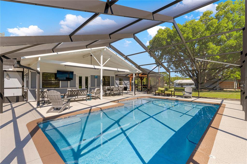 A screened-in patio features a swimming pool, outdoor seating, and a covered porch area — 2940 NE 49TH STREET, OCALA, FL