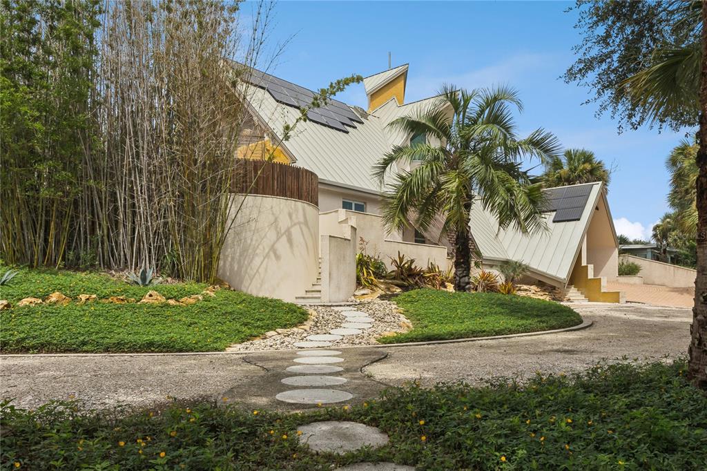 A modern house with a metal roof, solar panels, and a curved stone wall exterior — 1800 N PENINSULA AVENUE, NEW SMYRNA BEACH, FL