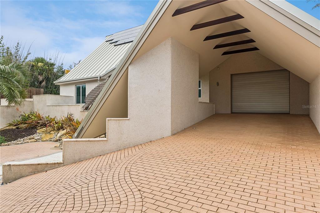 A paved driveway leads to a covered carport and garage attached to a modern house — 1800 N PENINSULA AVENUE, NEW SMYRNA BEACH, FL