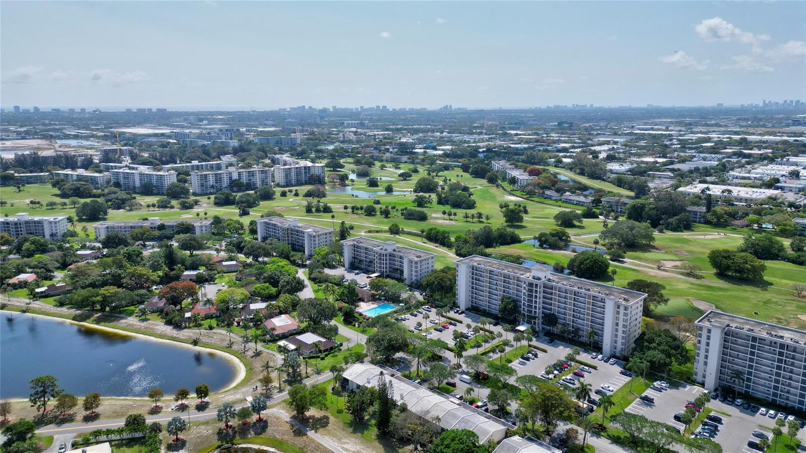 An aerial view shows several multi-story apartment buildings situated near a golf course and lake — 3050 N Palm Aire Drive # 505, Pompano Beach FL 33069, POMPANO BEACH, FL