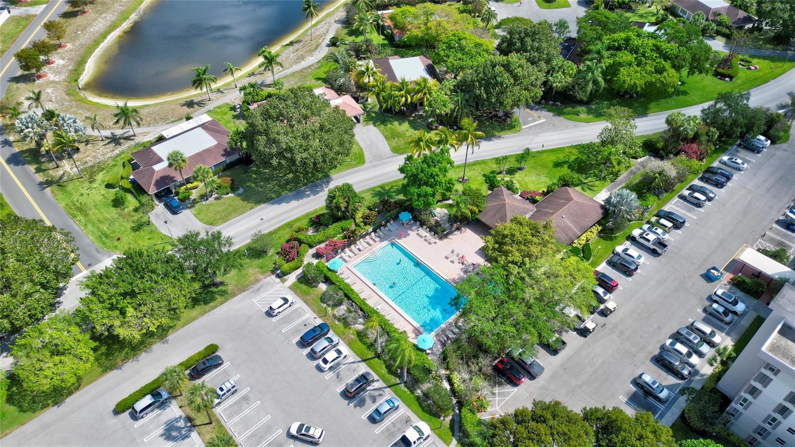 An aerial view shows a community swimming pool surrounded by parking lots and lush landscaping — 3050 N Palm Aire Drive # 505, Pompano Beach FL 33069, POMPANO BEACH, FL
