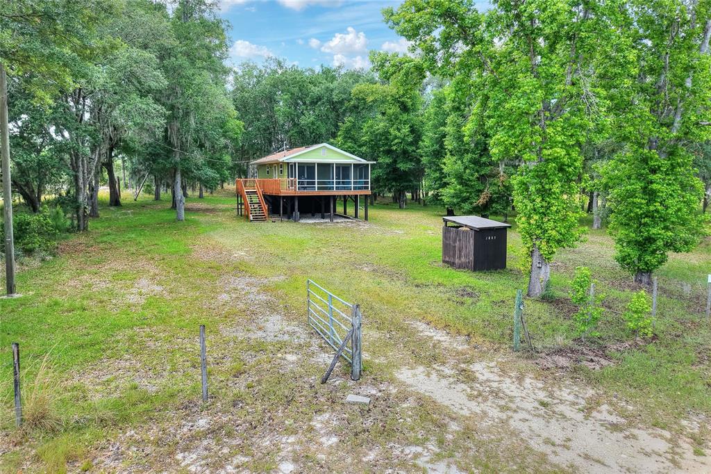 An elevated house with a screened porch sits on a grassy lot with trees — 1885 PFUNDSTEIN ROAD, LAKE WALES, FL
