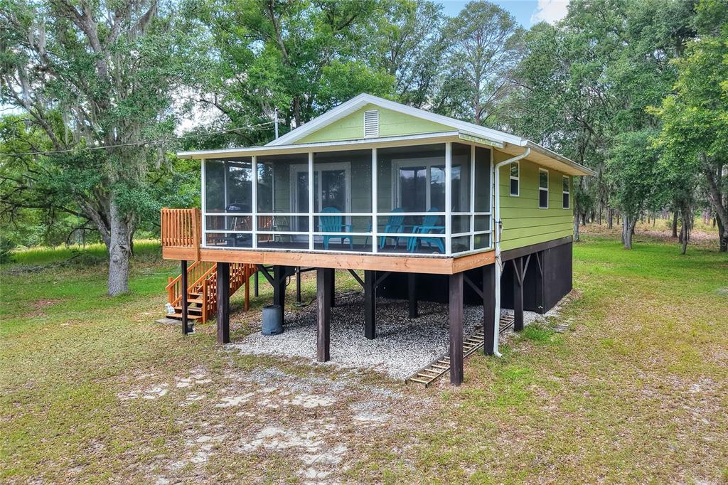 An elevated, light green house with a screened-in porch stands on wooden stilts — 1885 PFUNDSTEIN ROAD, LAKE WALES, FL