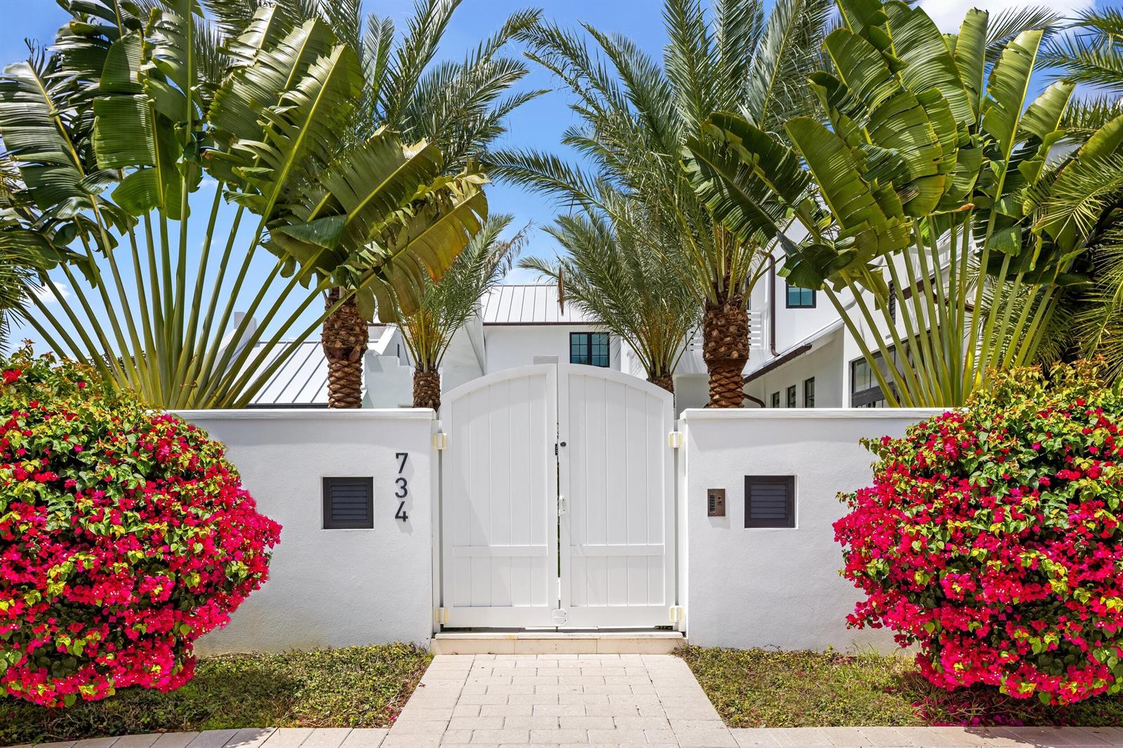 A white gate and wall are framed by palm trees and vibrant pink bougainvillea bushes — 734 S Ocean Boulevard, Delray Beach FL 33483, DELRAY BEACH, FL