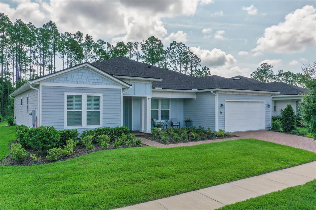 A light blue single-story house with a white garage and a brick driveway — 52 REVERIE DRIVE N, PALM COAST, FL