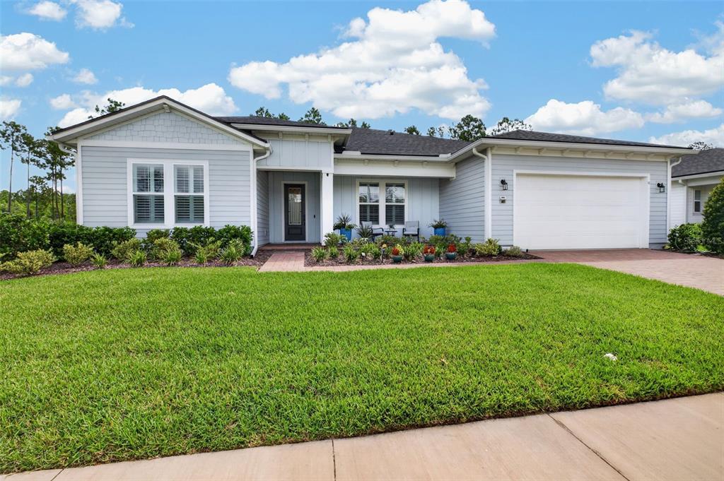 A light blue single-story house with a two-car garage and a landscaped front yard — 52 REVERIE DRIVE N, PALM COAST, FL