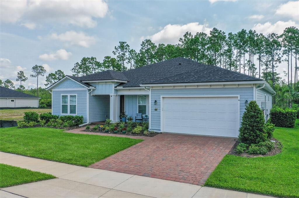 A light blue, single-story house with a brick driveway and a two-car garage — 52 REVERIE DRIVE N, PALM COAST, FL