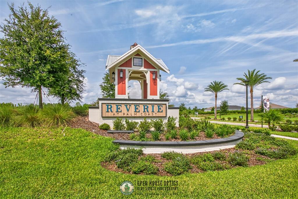 A brick entrance sign for Reverie at Palm Coast stands in a grassy landscape — 52 REVERIE DRIVE N, PALM COAST, FL