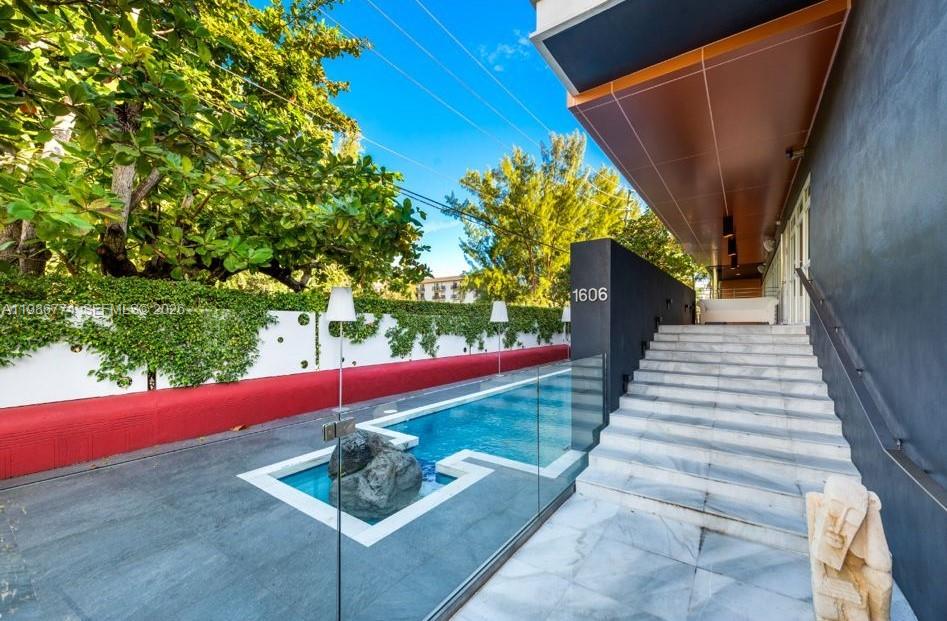 A modern outdoor swimming pool sits beside a wide marble staircase leading to a building entrance — 1606 S Bayshore Dr, Miami FL 33133, MIAMI, FL