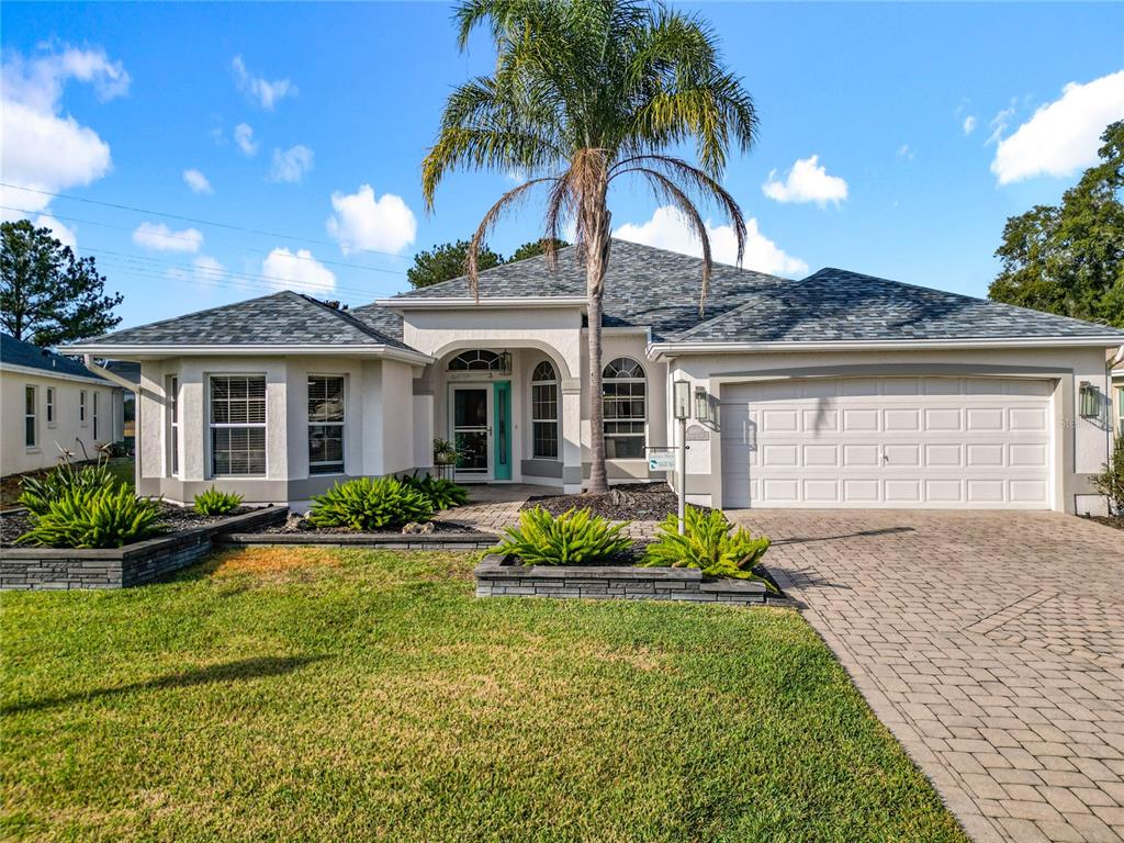 A single-story house with a paved driveway, palm tree, and landscaped front garden — 16816 SE 85TH SAPELO COURT, THE VILLAGES, FL