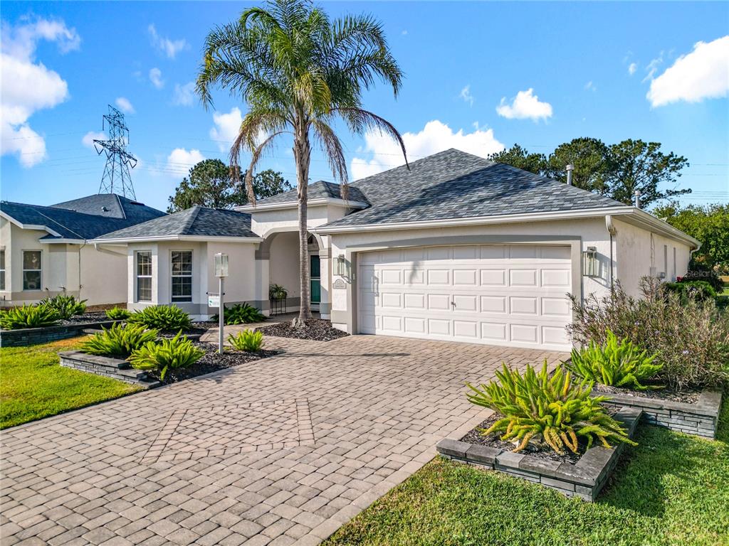 A single-story house with a paved driveway, a palm tree, and a two-car garage — 16816 SE 85TH SAPELO COURT, THE VILLAGES, FL