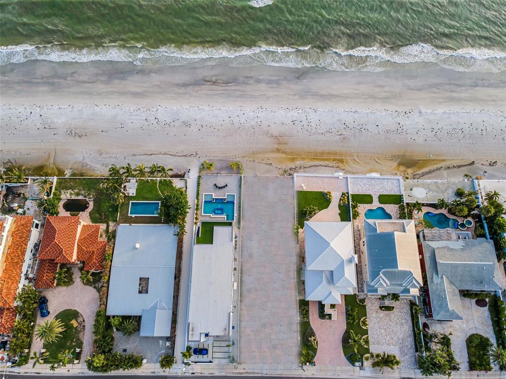 An aerial view shows several beachfront houses with swimming pools and paved driveways along the coast — 16200 GULF BOULEVARD, REDINGTON BEACH, FL