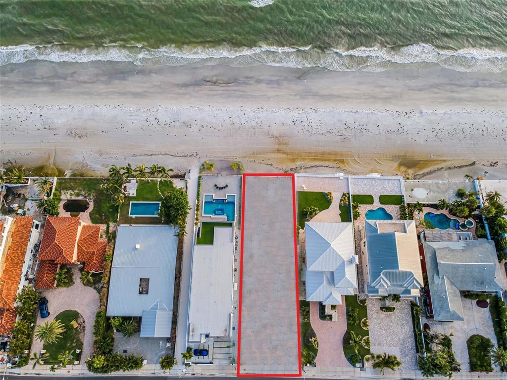An aerial view shows a vacant, rectangular beachfront lot outlined in red between two houses — 16200 GULF BOULEVARD, REDINGTON BEACH, FL