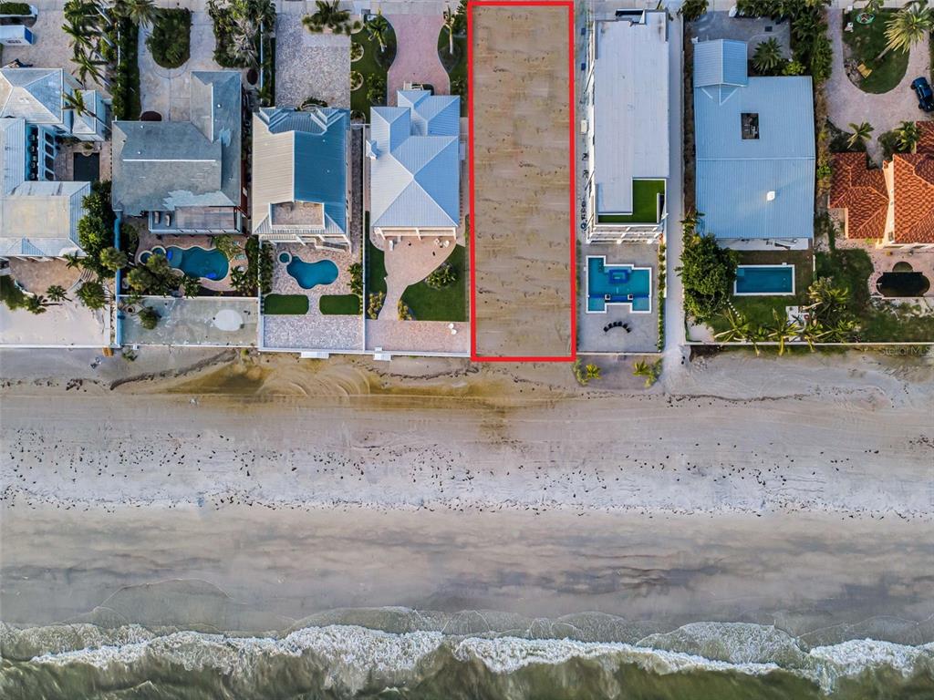 An aerial view shows a vacant, rectangular beachfront lot outlined in red between two houses — 16200 GULF BOULEVARD, REDINGTON BEACH, FL