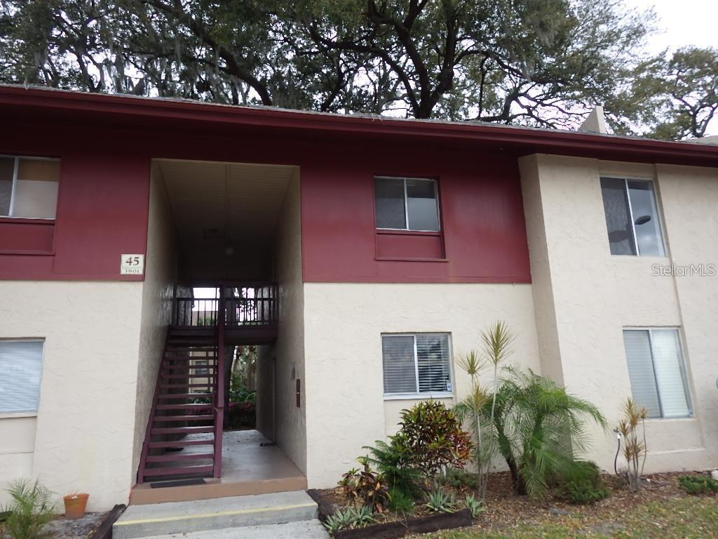 A two-story apartment building exterior features tan stucco walls, maroon trim, and an outdoor staircase — 3801 S LAKE DRIVE UNIT 247, TAMPA, FL