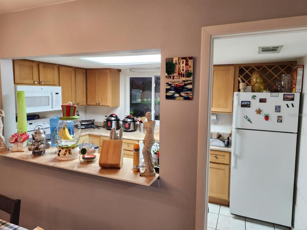 A kitchen features light wood cabinets, a white refrigerator, and a pass-through counter — 3801 S LAKE DRIVE UNIT 247, TAMPA, FL