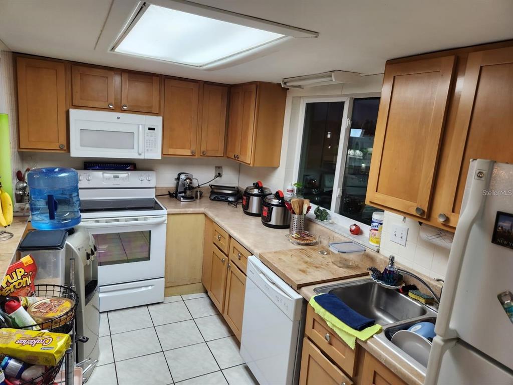 A kitchen features light wood cabinets, white appliances, a tiled floor, and a double sink — 3801 S LAKE DRIVE UNIT 247, TAMPA, FL