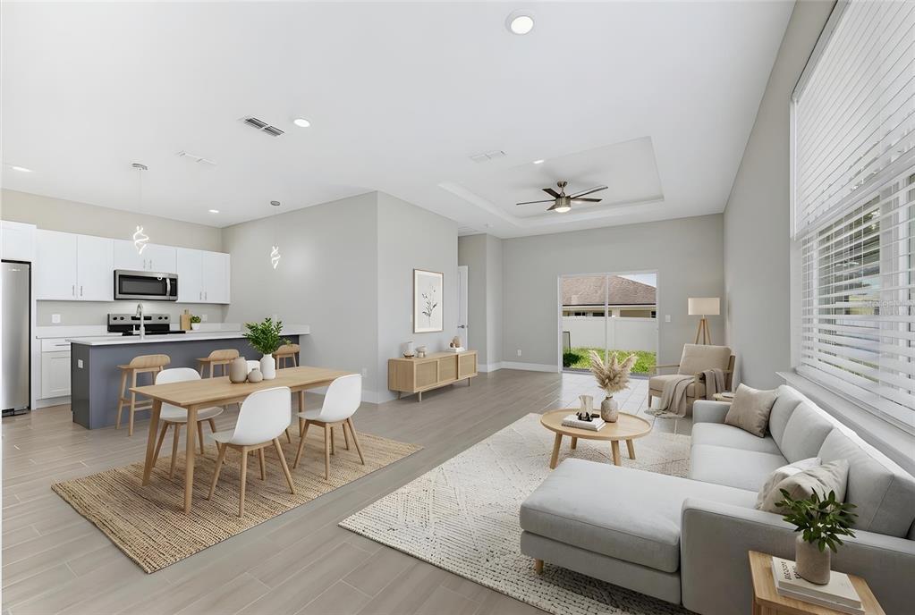 An open-concept living and dining area features a kitchen island, light wood floors, and furniture — 806 COLVILLE DRIVE, KISSIMMEE, FL