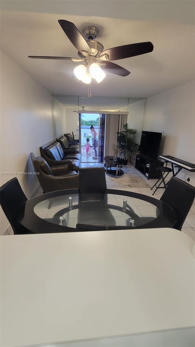 A dining area with a glass table leads into a living room with mirrored walls — 6820 W Flagler St # 207, Miami FL 33144, MIAMI, FL