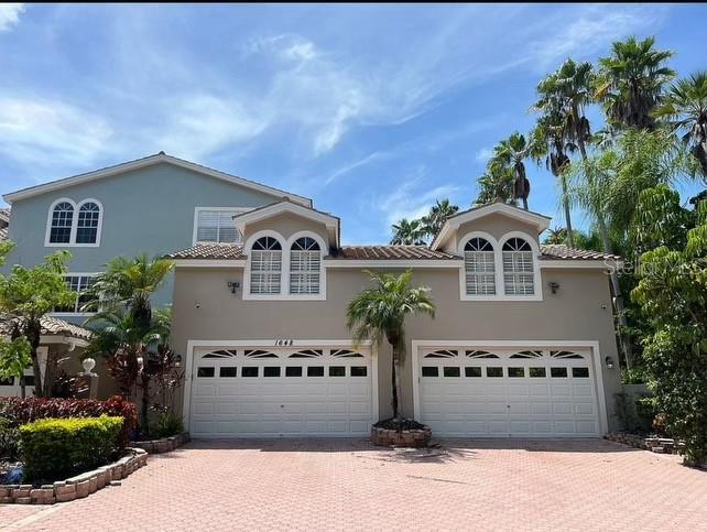 A two-story house with a beige facade, two garage doors, and a paved driveway — 1648 LAGO VISTA BOULEVARD, PALM HARBOR, FL