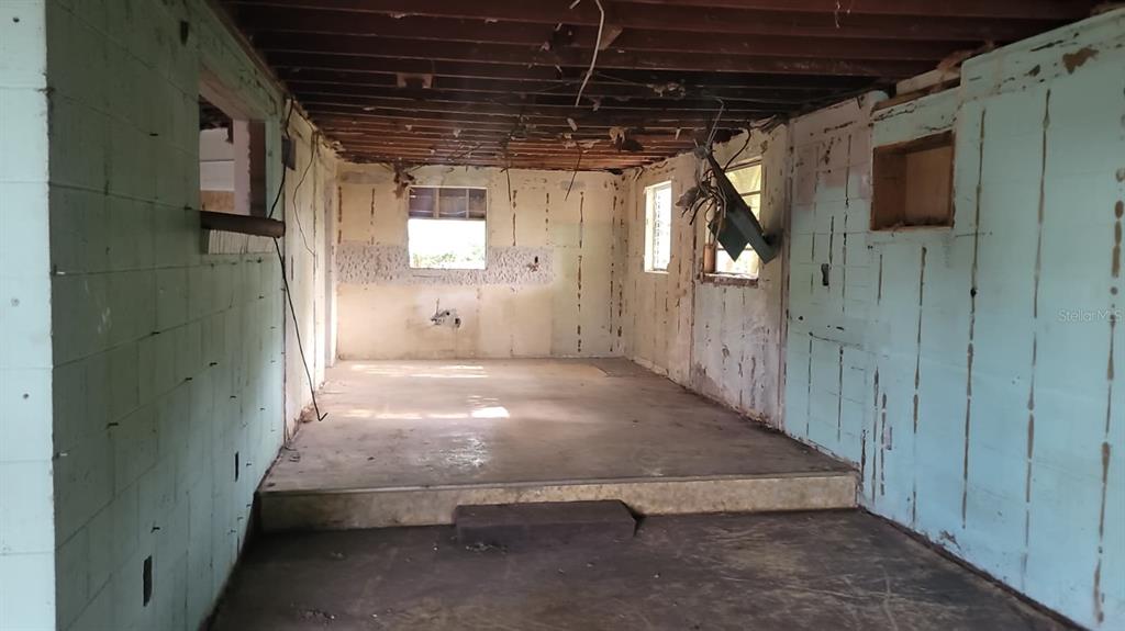An unfinished interior room features exposed ceiling joists, concrete floors, and bare wall panels — 1024 W FAIRBANKS AVENUE, ORLANDO, FL