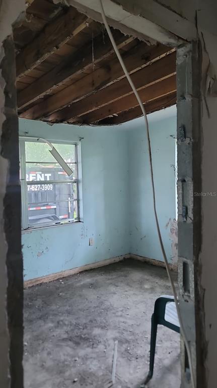 An unfinished room features exposed ceiling joists, light blue walls, and a concrete floor — 1024 W FAIRBANKS AVENUE, ORLANDO, FL