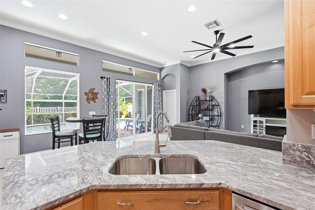 A kitchen island with a double sink overlooks a living room with a ceiling fan — 22608 KILLINGTON BOULEVARD, LAND O LAKES, FL