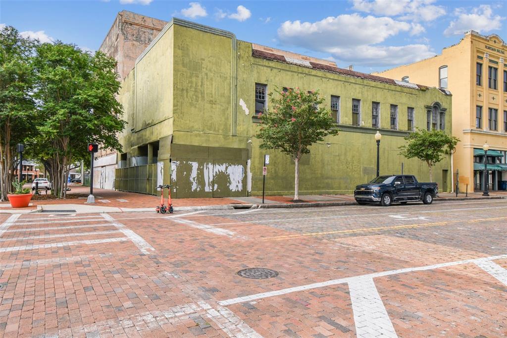 A weathered green two-story commercial building sits on a brick-paved street corner — 1001 N FRANKLIN STREET, TAMPA, FL