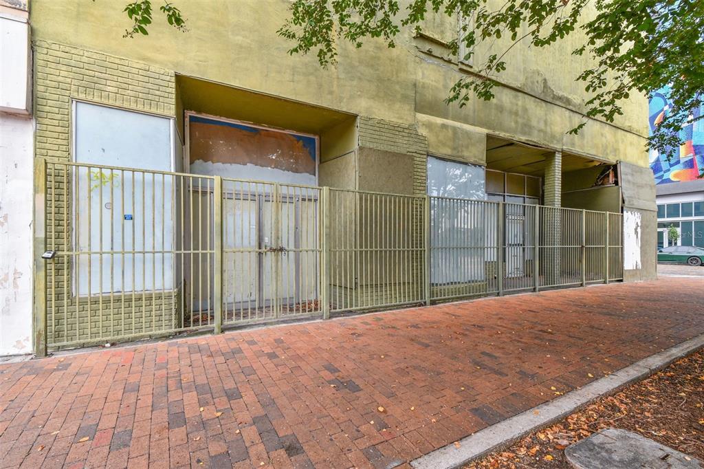 A street-level view of a weathered building exterior with boarded windows behind a metal fence — 1001 N FRANKLIN STREET, TAMPA, FL
