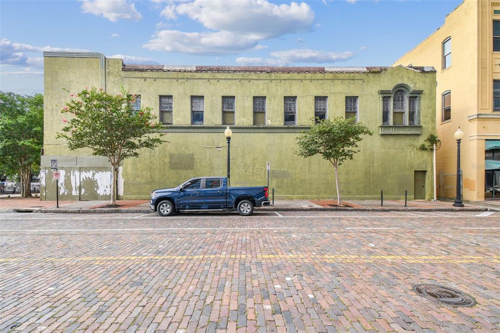 A blue pickup truck is parked on a brick street in front of a green building — 1001 N FRANKLIN STREET, TAMPA, FL