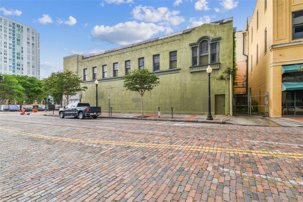 A green brick building with multiple windows sits along a street paved with red bricks — 1001 N FRANKLIN STREET, TAMPA, FL