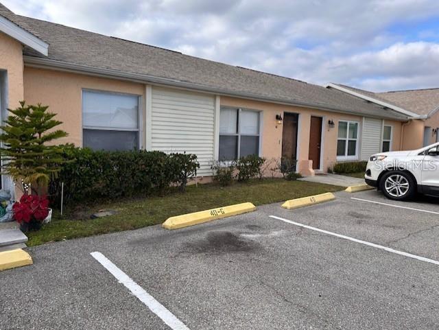 A single-story peach-colored apartment building with a parking lot in the foreground — 40 E COUNTRY COVE WAY, KISSIMMEE, FL