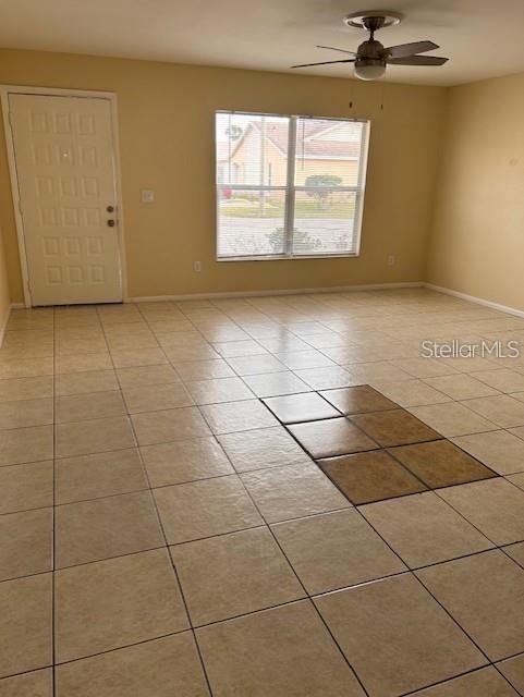 An empty room features light-colored tile flooring, a ceiling fan, and a white entry door — 40 E COUNTRY COVE WAY, KISSIMMEE, FL