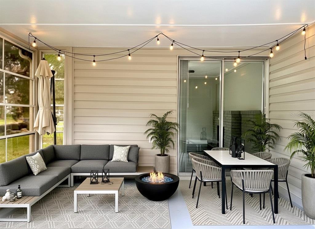 A covered patio features a gray sectional sofa, a dining set, and a fire pit — 5045 GREEN KEY ROAD, NEW PORT RICHEY, FL