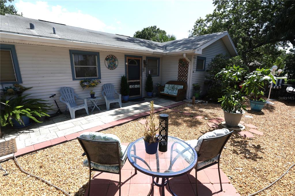 A patio area features a glass table, chairs, and gravel landscaping in front of a house — 915 DEMPSEY STREET, CLEARWATER, FL