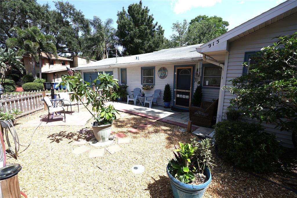A gravel courtyard sits in front of a single-story house with light-colored siding — 915 DEMPSEY STREET, CLEARWATER, FL