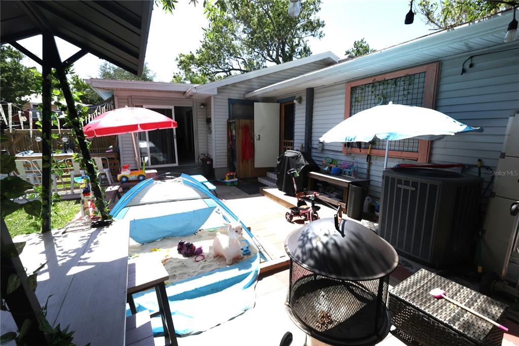 A backyard patio features a sandbox, umbrellas, a fire pit, and a house exterior — 915 DEMPSEY STREET, CLEARWATER, FL
